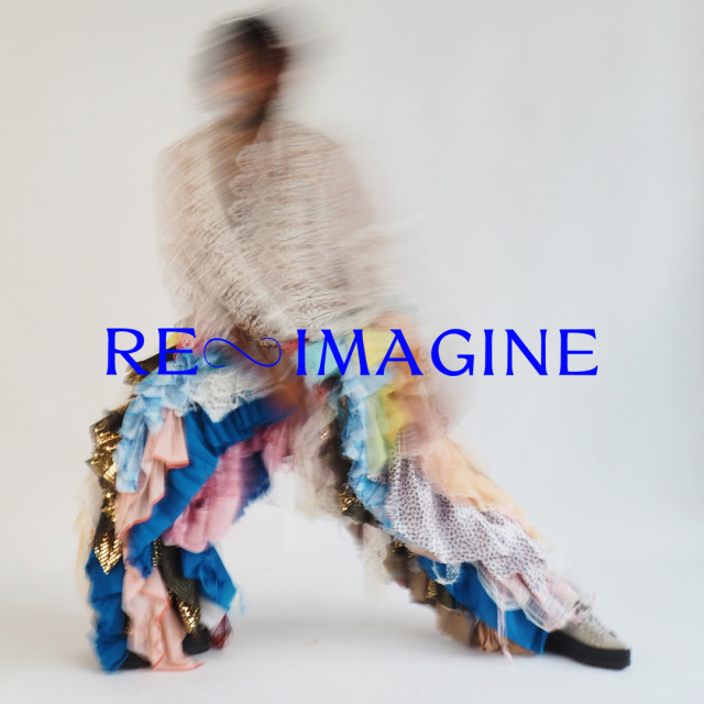 Een wazige, bewogen foto van een persoon met een wit kanten top aan en een broek van heel veel verschillende soorten stoffen. stoffen. In blauwe letters staat geschreven "Re-Imagine"
