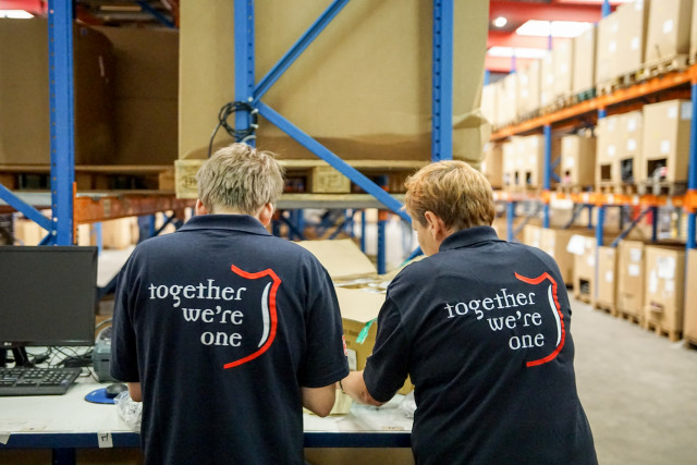 Twee mensen met Leger des Heils shirts zijn aan het werk in het sorteercentrum