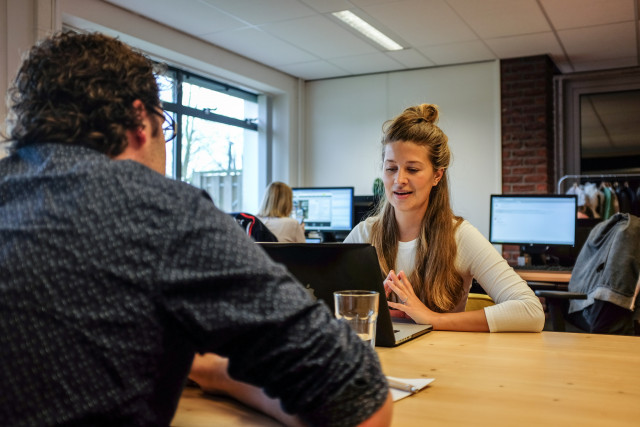 Twee mensen zitten op kantoor te overleggen.